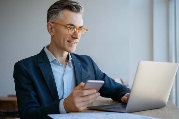 Portrait of mature businessman using laptop typing