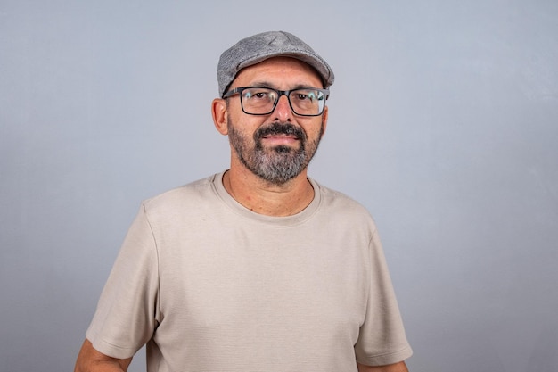 Portrait of mature businessman wearing eyeglasses over gray background Happy 60s senior brazilian man looking at camera isolated over gray wall with copy space