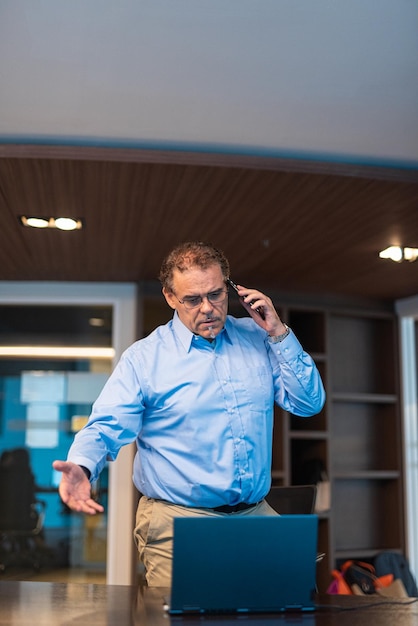 Portrait of mature businessman working and looking angry while talking on phone