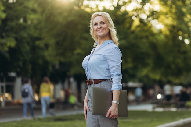 Portrait of a mature businesswoman holding a laptop Happy senior woman office worker Women of the 50s The concept of work Freelance Success