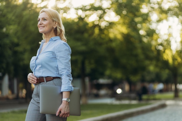 Portrait of a mature businesswoman holding a laptop Happy senior woman office worker Women of the 50s The concept of work Freelance Success