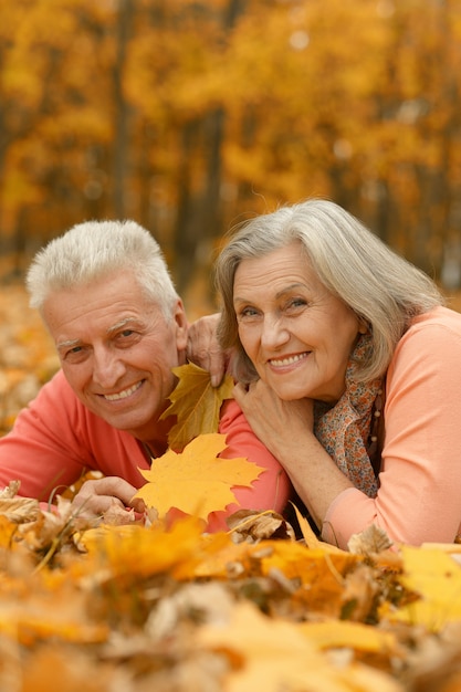 Portrait of a mature couple lying on leaves in the autumn park