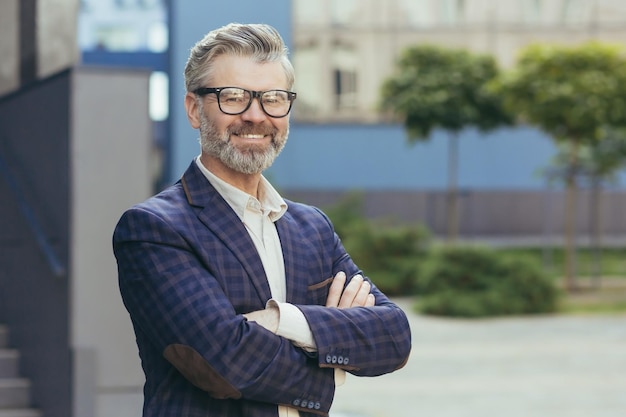 Portrait of mature grayhaired investor senior man in glasses looking at camera and gesturing