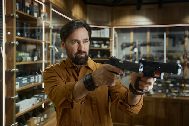 Portrait of mature male in shop merchant with two handguns aiming