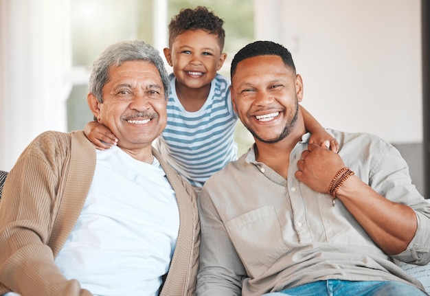 Portrait of a mature man sitting with his son and holding his grandson at home