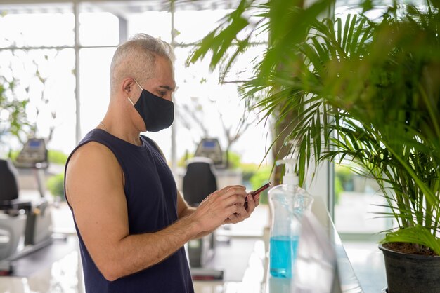 Portrait of mature Persian man with mask for protection from corona virus outbreak social distancing at the gym