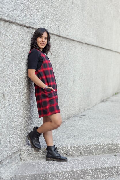 Portrait of a Mexican woman with a dress leaning against the wall of a museum with copy space