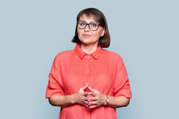 Portrait of mid adult woman in red dress looking at camera on gray isolated background