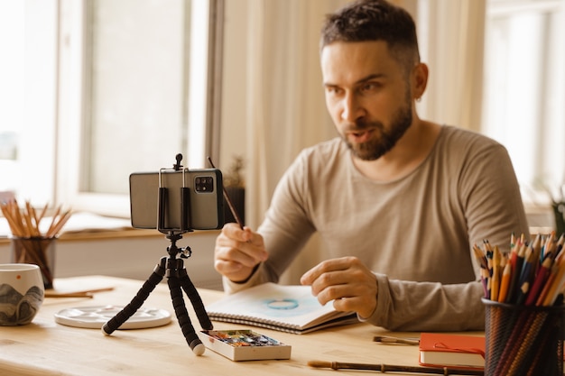 Portrait of midadult artist male dark haired man smiling happy making online art class for students