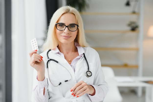 Portrait of middle age female doctor is wearing a white doctor's coat with a stethoscope around her neck Smiling physician standing at private clinic