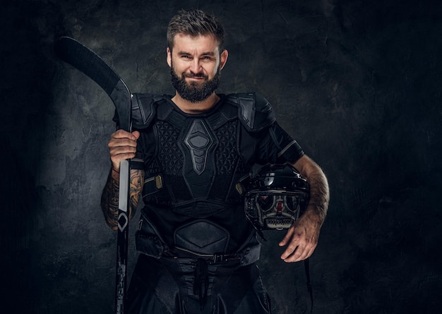 Portrait of middle aged handsome man with hockey stick and uniform.