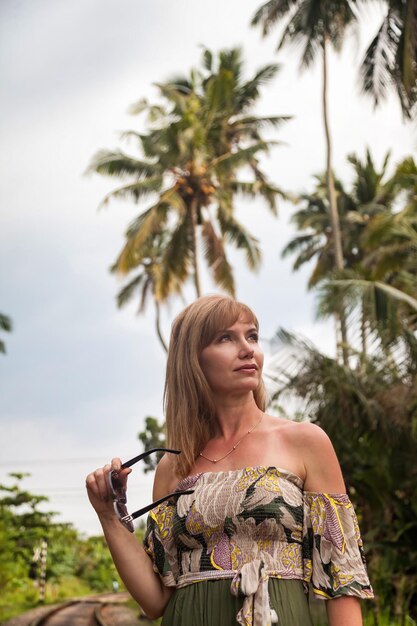 Portrait middle aged woman in Sri Lankan at tropical jungles background looking away