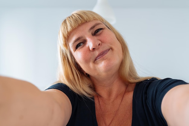 Portrait middleaged woman blonde grimacing in front mirror