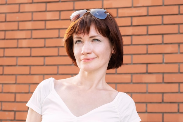 Portrait of a middleaged woman in front of a red brick wall