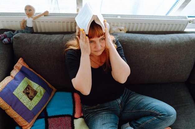 Portrait middleaged woman reading book while sitting on sofa