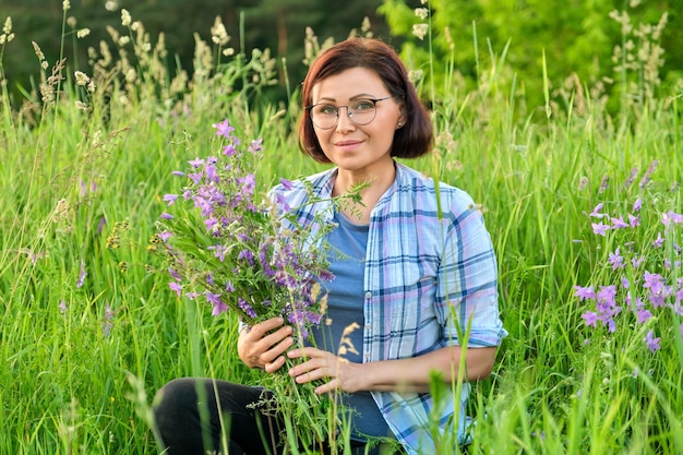 Portrait of a middleaged woman with a bouquet of wildflowers in nature