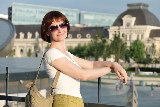 Portrait of a middleaged woman with sunglasses on the background of the city square