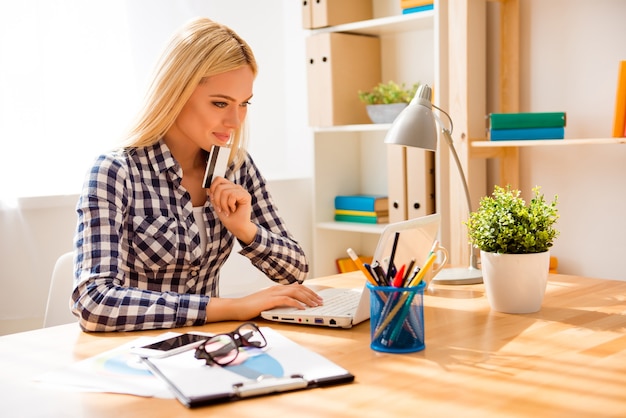 Portrait of minded woman holding bank card and doing shopping