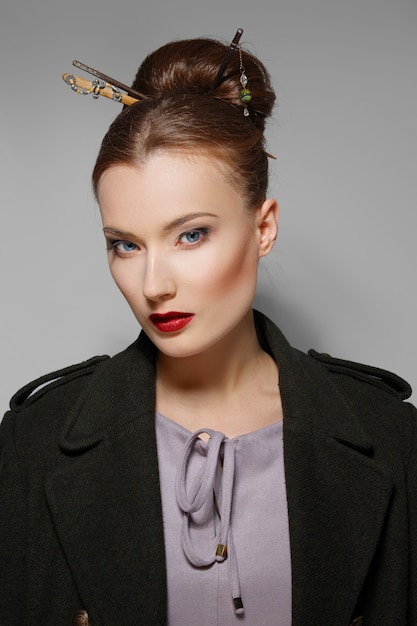 Portrait of model with oriental hairstyle, red lips and blue eyes. Perfect healthy skin.