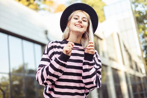 Portrait of modern hipster girl in hat and glasses outdoors