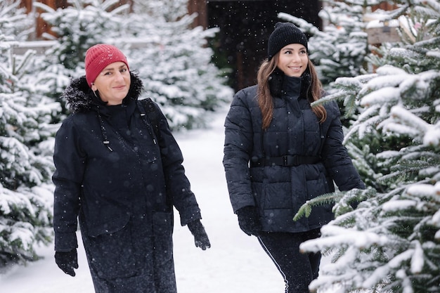 Portrait of mom and daughter choose fir tree for christmas holidays