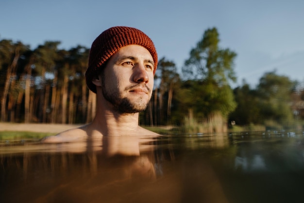 Portrait of morning swim and cold treatment young man soaks in the winter lake at morning male perso