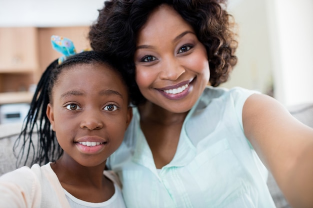 Portrait of mother and daughter sitting on sofa in living room