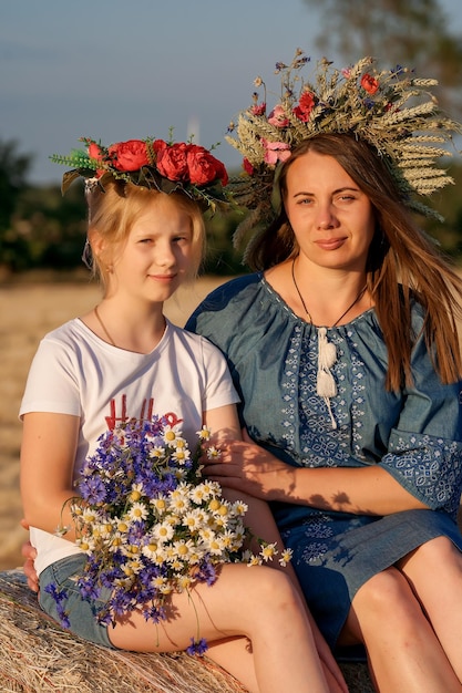 Portrait of mother and daughter in Ukrainian traditional outfits with wreaths on her head Constitution day Patriotic holiday Woman and child