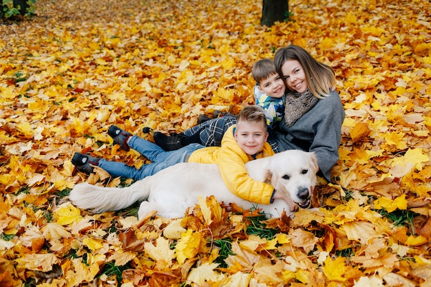 Portrait of a mother with two sons and a dog in an autumn park