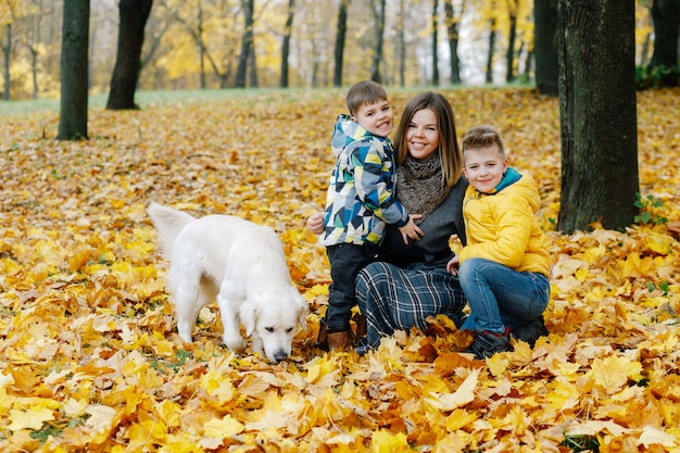 Portrait of a mother with two sons and a dog in an autumn park