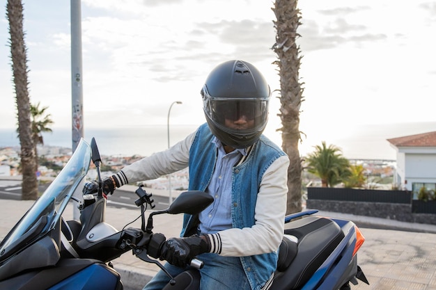 Portrait of a motorcyclist sitting on his scooter with his helmet on road safety concept