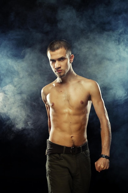 Portrait of a muscular male model against dark background with