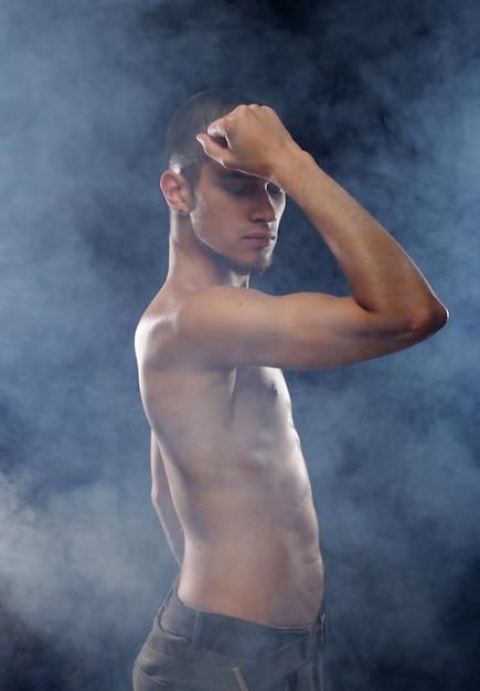 Portrait of a muscular male model against dark  background with