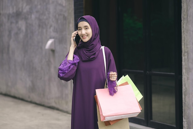 Portrait Muslim woman wearing hijab walking talking on the phone and shopping