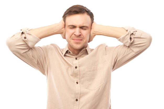 Portrait of nervous young man covering ears with hands isolated on white background Stress emotional burnout selfdoubt concept