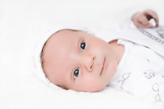 Portrait of a newborn baby boy in a cap on a white