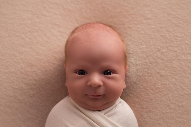 Portrait of a newborn baby with a smile on his face on a beige background