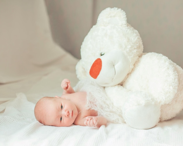 Portrait of a newborn baby with a soft toy in the parents ' bed