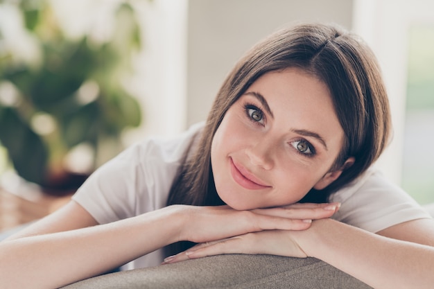 Portrait of nice adorable young girl look in camera sit divan wear casual style clothes in house indoors