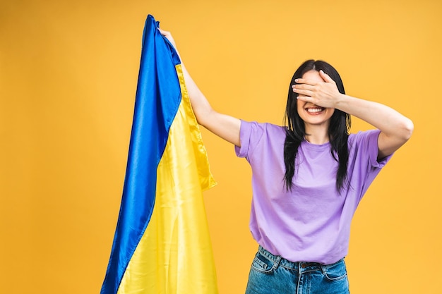 Portrait of nice beautiful lovely glad cheerful woman holding in hands Ukrainian flag having fun isolated over yellow pastel color background