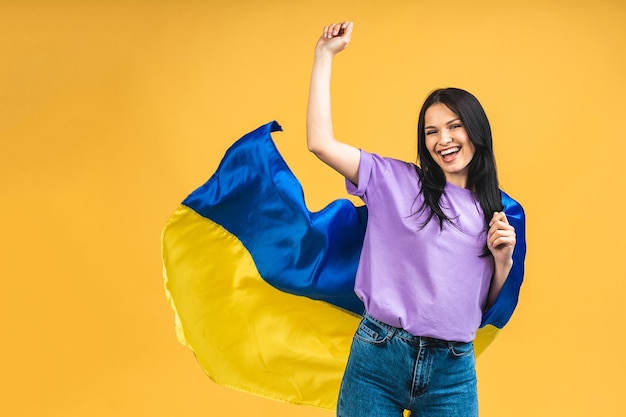 Portrait of nice beautiful lovely glad cheerful woman holding in hands Ukrainian flag having fun isolated over yellow pastel color background