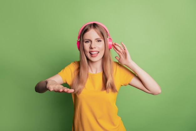 Portrait of nice glad funky dj lady listen music play track wear headphones yellow t-shirt on green background