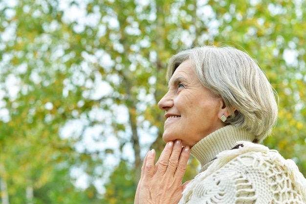 Portrait of nice smiling old woman posing in forest