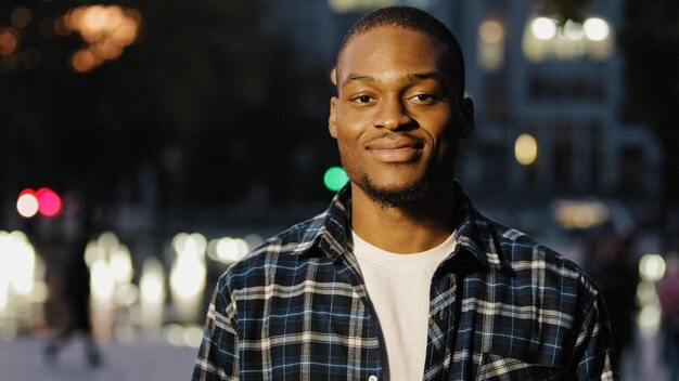 Portrait in night city evening outdoors african american friendly successful man guy in plaid shirt