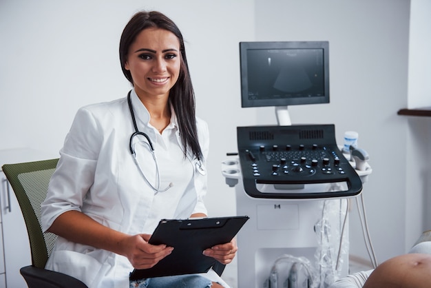 Portrait of obstetric doctor that sits in the clinic room with ultrasound device.