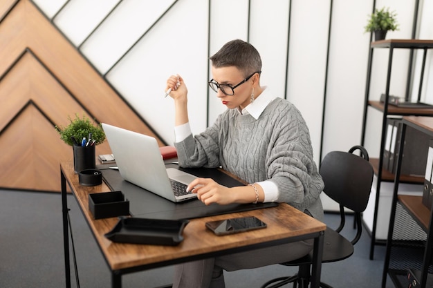 Portrait of an office worker in a company sitting at a desktop with a laptop