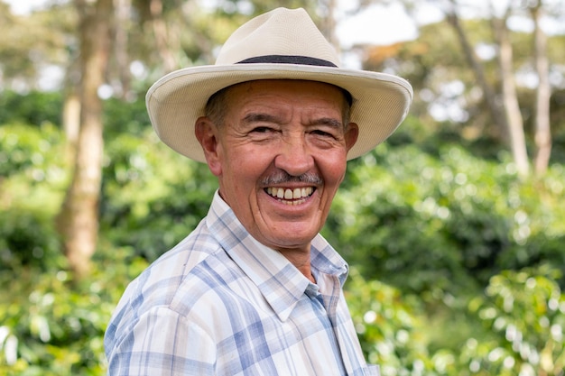 Portrait of an old Colombian peasant man wearing a hat and looking at the camera with a big smile