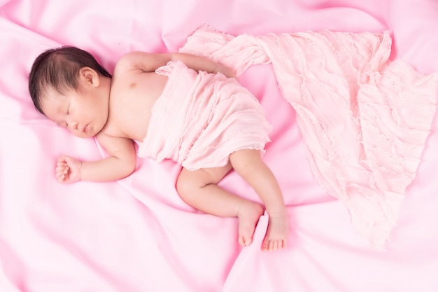 Portrait of a one month old sleeping, newborn baby girl on a pink blanket. Concept portrait studio fashion newborn.