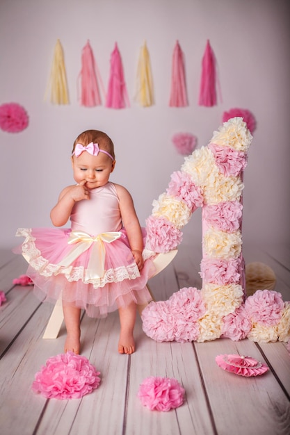 Portrait of one yearold baby girl with paper party deko and big number one