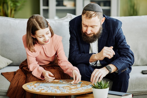 Portrait of orthodox jewish father playing puzzle game with young daughter